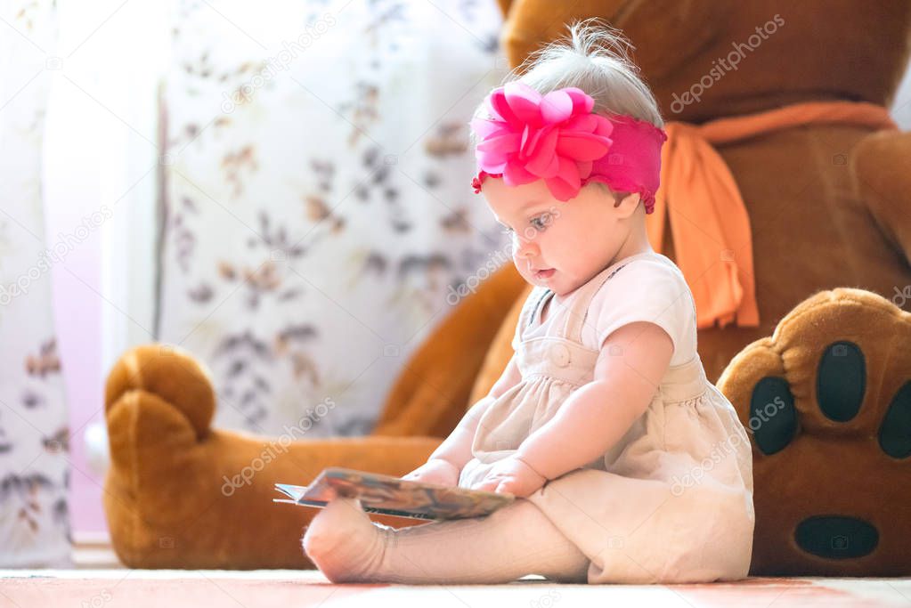 10 months old baby girl examining a book