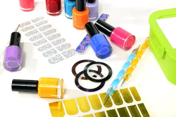 Table full of manicure ustensils, coloured nail polish,nail decals stickers, striping tape, nail file, dotting nail pens, vinyl sheets.  Nails art accesories isolated on white. — Stock Photo, Image