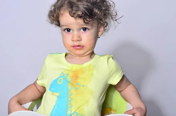 Beautiful curly toddler looking surprised, boy being upset because he got dirty while eating — Stock Photo, Image