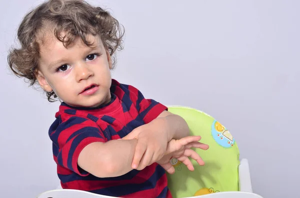 Beautiful curly toddler playing with his hands — Stock Photo, Image