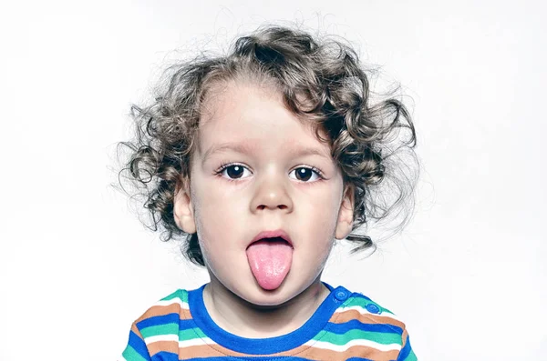 Beautiful curly toddler being naughty, boy with his tongue out — Stock Photo, Image