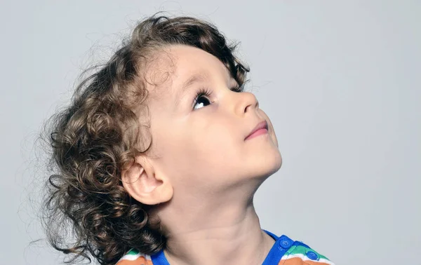 Hermoso niño rizado mirando hacia arriba, niño sorprendido y mirando a sus padres —  Fotos de Stock