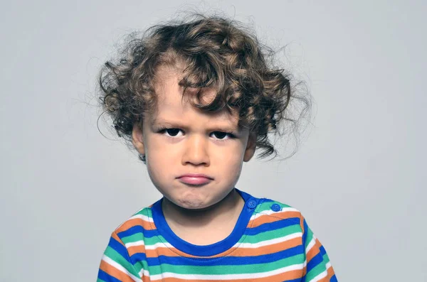 Hermoso niño rizado mirando enojado, chico triste siendo travieso —  Fotos de Stock