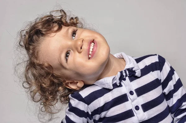 Bela criança encaracolado olhando para cima e sorrindo feliz com seus dentes brancos — Fotografia de Stock