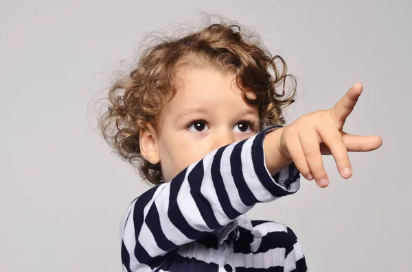 Beautiful curly toddler looking forward and showing to something with his finger — Stock Photo, Image