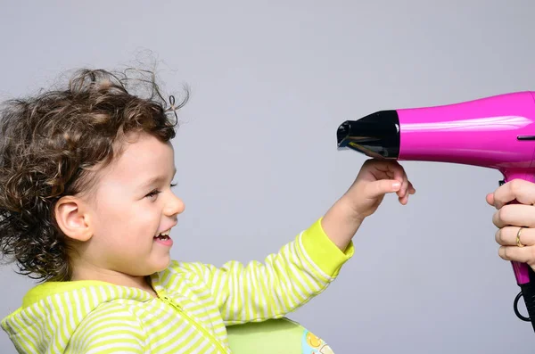 Mothers hands drying her beautiful boy after a bath. Toddler laughing, joking and playing with the hairdryer that is blowing his curly hair — Stock Photo, Image