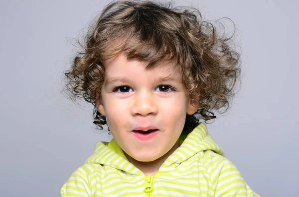 Retrato de un chico hermoso con el pelo largo y rizado. Niño mirando sorprendido y jugando — Foto de Stock