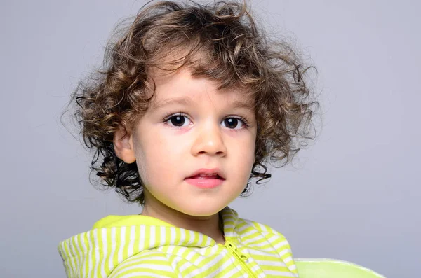 Retrato de un chico hermoso con el pelo largo y rizado. Niño mirando sorprendido y jugando —  Fotos de Stock