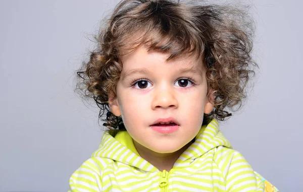 Retrato de um menino bonito com cabelos longos encaracolados. Criança olhando surpreso e jogando — Fotografia de Stock