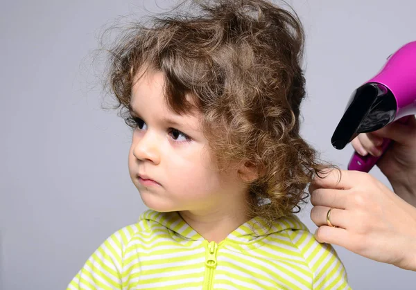 Mothers hands drying her beautiful boy after a bath. Toddler looking upset and looking the other way while the hairdryer is blowing his curly hair — Stock Photo, Image
