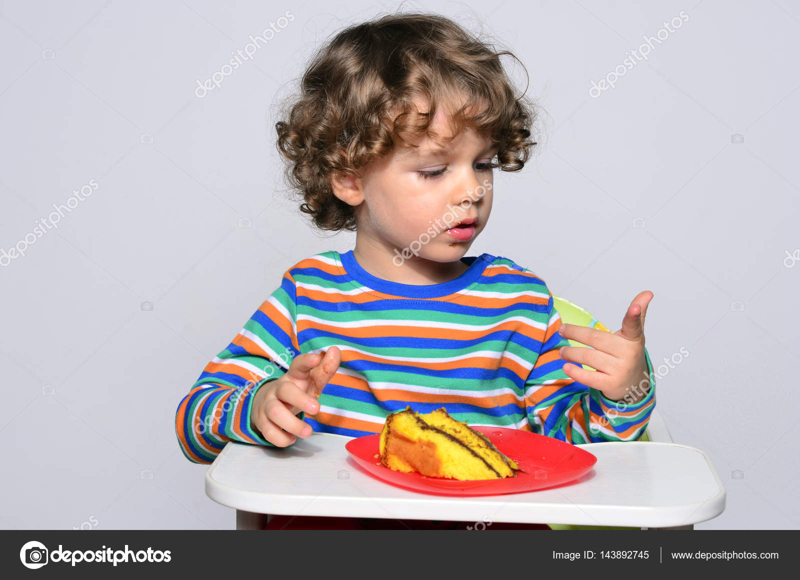 Ragazzino fare mentre si mangia una torta al cioccolato Ragazzo di bei capelli ricci mangiare dolci Bambino nel seggiolone essendo affamati — Foto