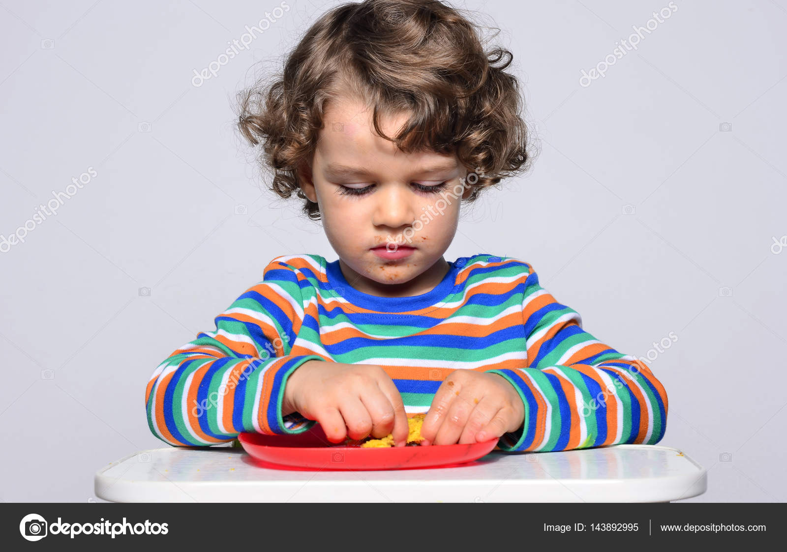 Ragazzino fare mentre si mangia una torta al cioccolato Ragazzo di bei capelli ricci mangiare dolci Bambino nel seggiolone essendo affamati — Foto