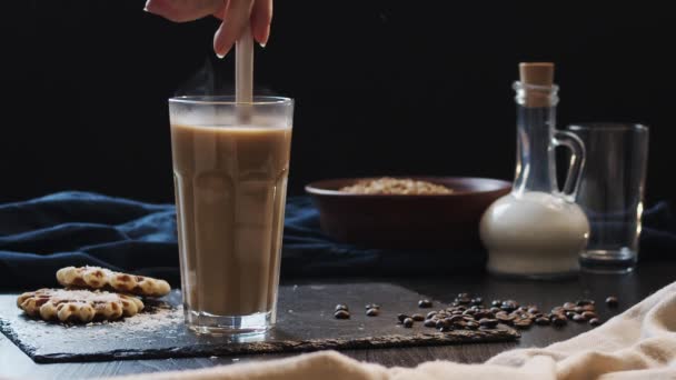 Kaffe med mælk omrøres med en ske i et gennemsigtigt glas, slow-motion video side view – Stock-video