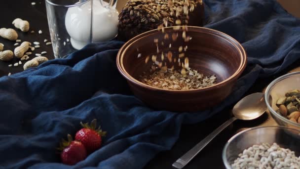 Muesli se vierte en una placa de arcilla, toalla azul, vista superior, video en cámara lenta — Vídeos de Stock