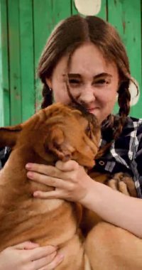 Hamaktaki kız köpekle oynuyor, dikey çerçeveli, yakın plan.