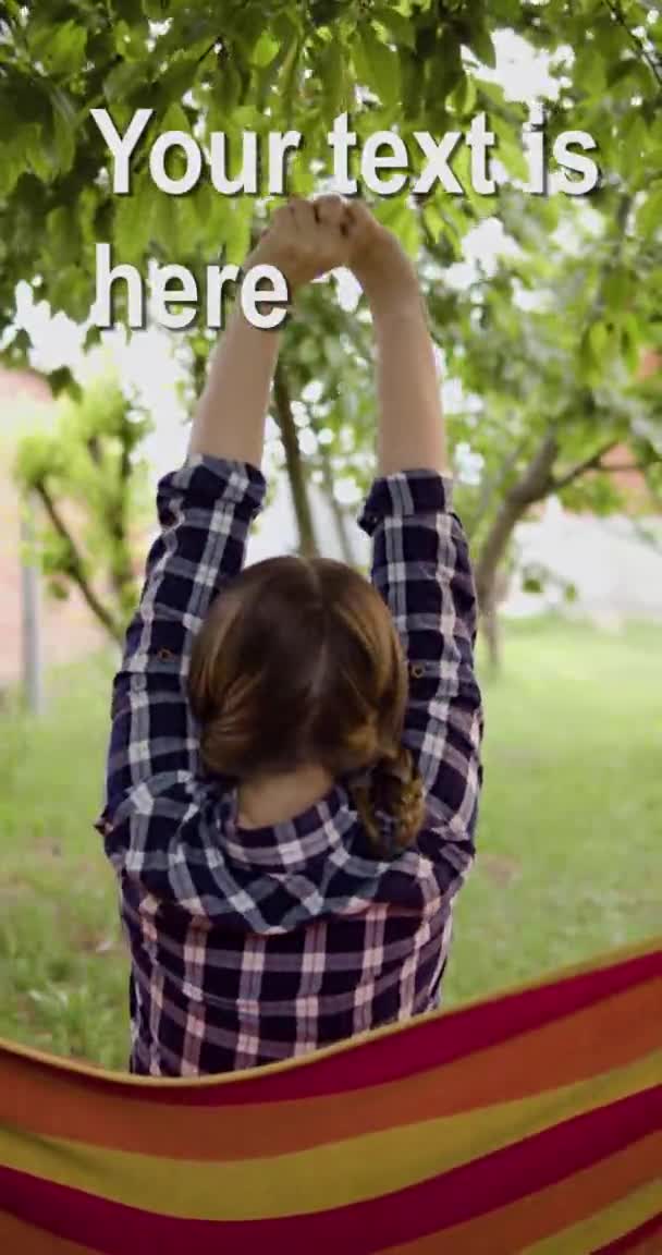 Девушка садится спиной к раме, вытягивает руки вверх, качается на гамаке, копирует пространство, вертикальные рамки — стоковое видео