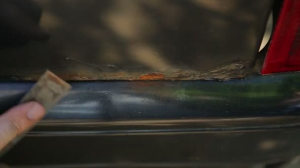 Un homme nettoie la rouille sur un corps de voiture avec un grattoir. Laps de temps .