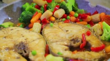 Izgara için maşa bir tavada sebze ve balık kavurma karıştırın.