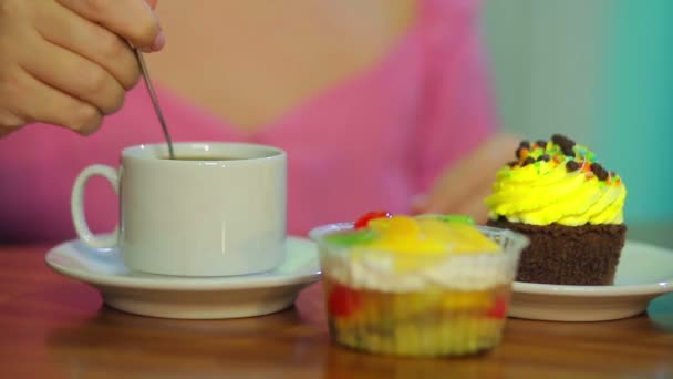 Female hand interferes with coffee in a cafe at the table with cakes. — Stock Video