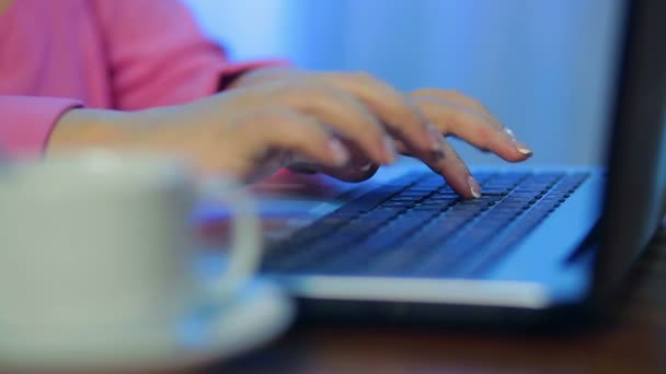 Les mains féminines travaillent sur l'ordinateur au premier plan une tasse de café dans le flou — Video