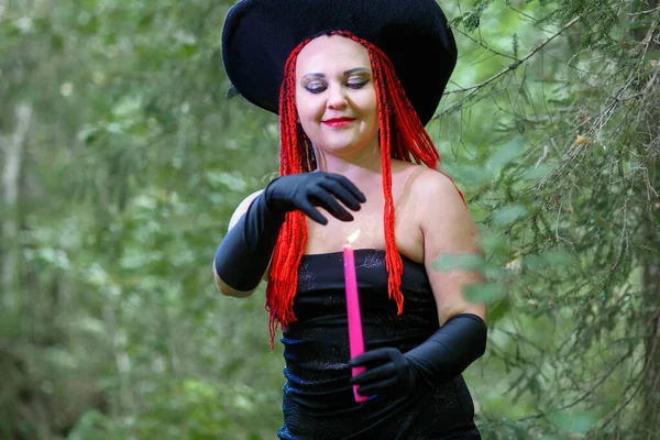 Bruja seductora con el pelo rojo en el bosque se dedica a la magia del amor con una vela . — Foto de Stock