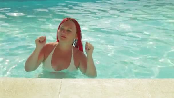 Zsidó nő fehér fürdőruhában vörös hajtánccal a medencében nyaralni.