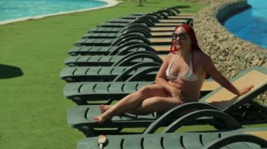 Modern bir Yahudi kadın havuz kenarında iskemlede güneşlenmekten hoşlanıyor..
