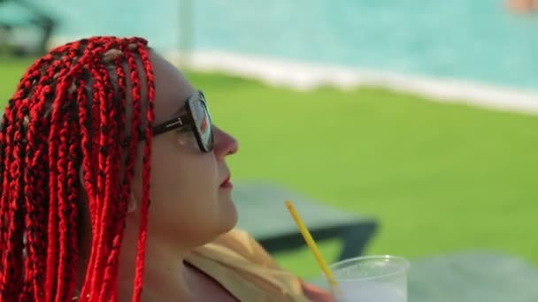 Жінка біля басейну п'є молочний коктейль із соломи . — стокове відео