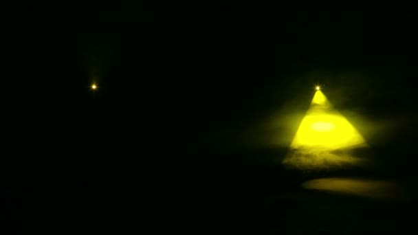 Żółte promienie reflektorów profilowych w ciemności w kocu dymnym. — Wideo stockowe