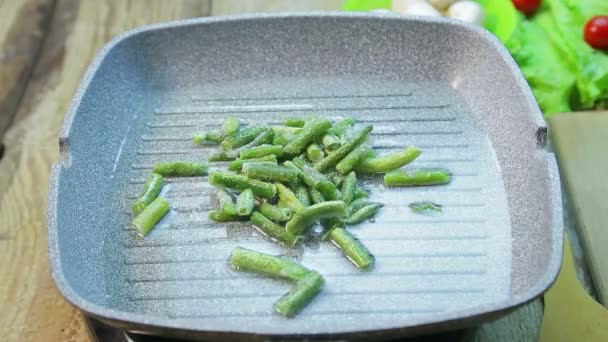 Una mano femminile mette i fagioli in una padella con un olio di giri di tempo delizioso . — Video Stock