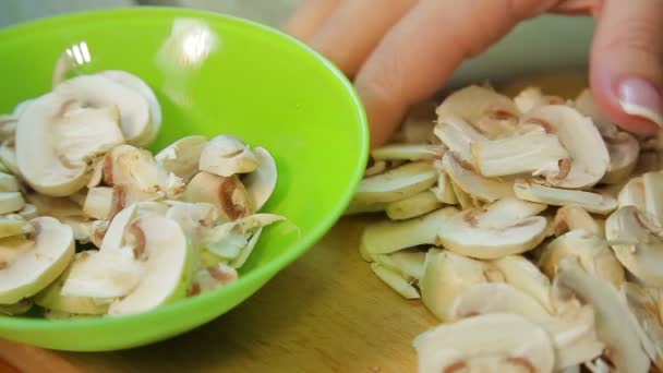 Vrouwelijke hand zet gesneden champignons in een bord. — Stockvideo