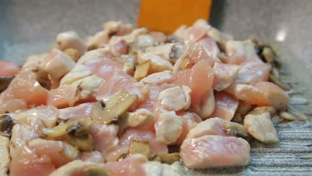 Filet z kurczaka w oleju jest mieszany na patelni z drewnianą łopatką — Wideo stockowe