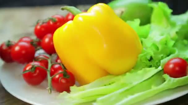 Tomates cherry frescos, saolat, pimienta y aguacate en un plato rota en un círculo — Vídeo de stock