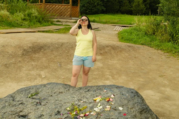 Touristin blickt durch Fernglas in der Nähe eines riesigen Steins. — Stockfoto