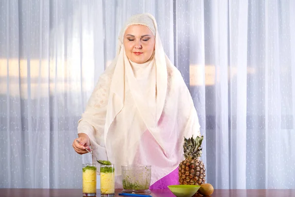 Eine junge Muslimin in hellem Schal steht am Tisch mit Obst und gibt Kiwi-Püree in ein Glas. — Stockfoto