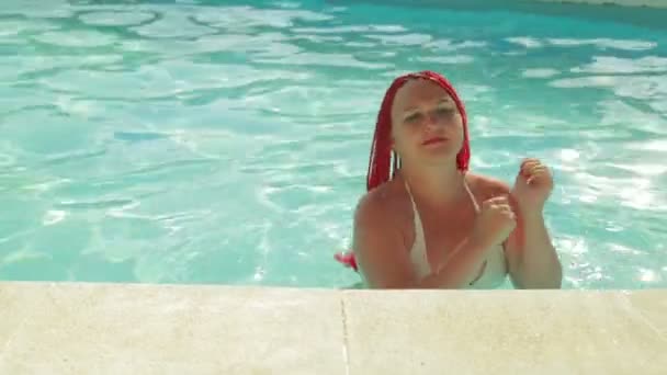 Gebräunte Frau mit Zöpfen tanzt im Pool — Stockvideo