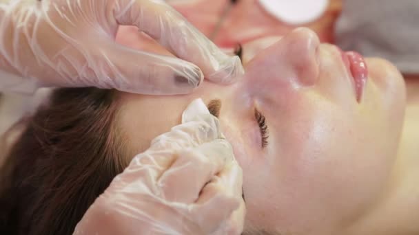 Косметолог миє хну з брів клієнта і наносить спеціальний крем — стокове відео