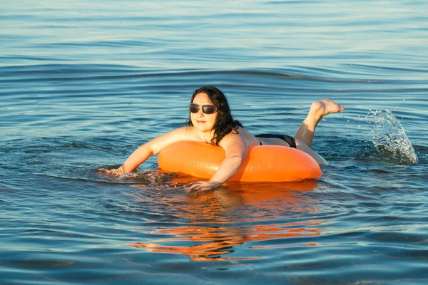 Een brunette vrouw zwemt in de zee op een zwemmen cirkel. — Stockfoto