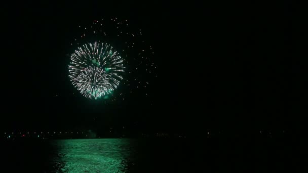 Bunte Feuerfunken entzünden ein festliches Feuerwerk am Nachthimmel über dem Fluss, das sich im Wasser spiegelt. — Stockvideo