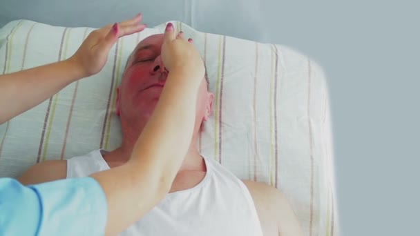 Egy női kozmetikus hidratáló maszkot tesz egy férfi arcára. Az átlag — Stock videók