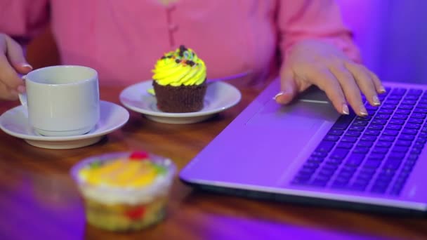Vrouwelijke handen werken op een computer, eten gebak en neem koffie. — Stockvideo