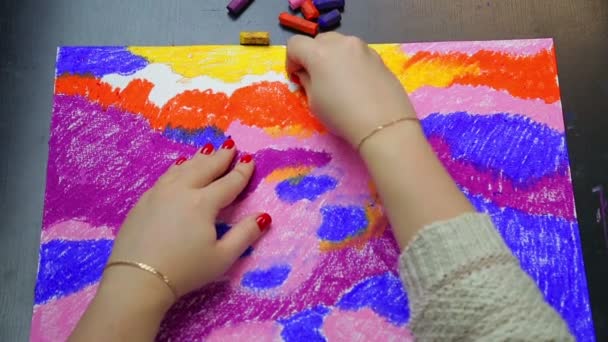 Een vrouw completeert werk aan een pastel lucht landschap bij zonsondergang in oranje krijt — Stockvideo