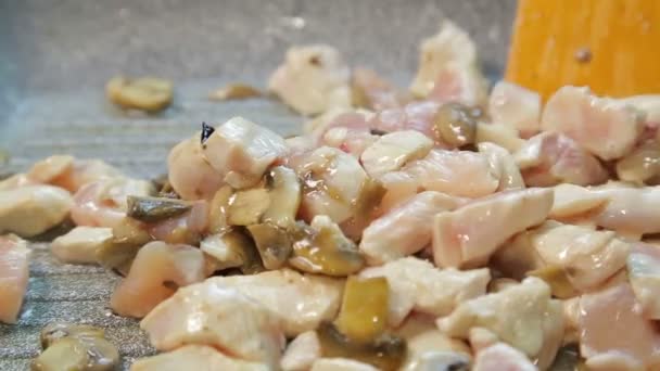 Il filetto di pollo sott'olio viene mescolato in una padella con una spatola di legno — Video Stock