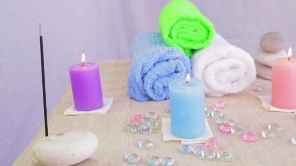 Стол в СПА салоне со свечами, полотенцами и камнями для терапии — стоковое видео