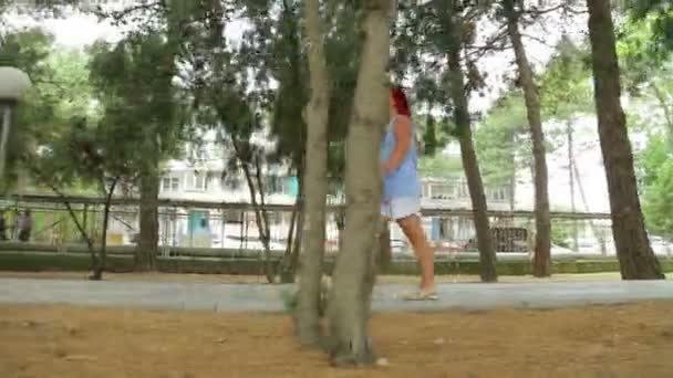 Uma mulher no parque caminhando ao longo do beco — Vídeo de Stock
