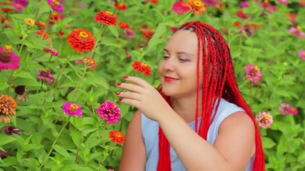 Mulher com cabelo vermelho admira flores bonitas no parque . — Vídeo de Stock