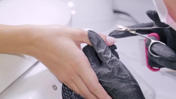 Femme manucure en gants dans un salon de beauté coupe la cuticule sur les ongles d'un client — Video