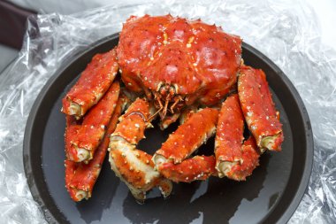 Fırınlanmış Kamçatka yengeci siyah bir tabakta..