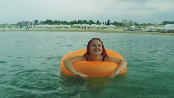 En ung kvinna simmar i havet i en badcirkel. — Stockvideo