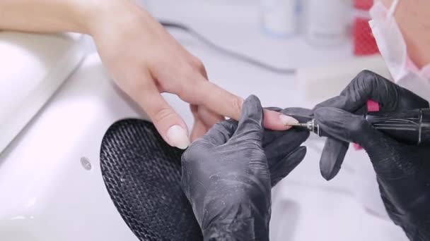 Manicurist kvinde i handsker i skønhedssalonen behandler neglebånd på neglene af klienten – Stock-video